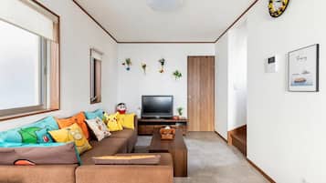 Un salón con sofá, televisor y cojines decorativos.