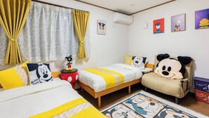 Una habitación con dos camas, un sillón de Mickey Mouse y varias decoraciones con temática de Mickey Mouse.