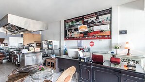 Cocina moderna con electrodomésticos de acero inoxidable, una isla de madera y una zona de estar con una silla de mimbre.