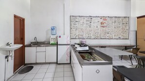 Una cocina compacta con un lavamanos, un refrigerador, un dispensador de agua y un calendario grande en la pared.