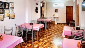 A dining area with tables covered in pink tablecloths, wooden parquet flooring, and star-shaped ceiling decorations. - Royal Selection (Manali)