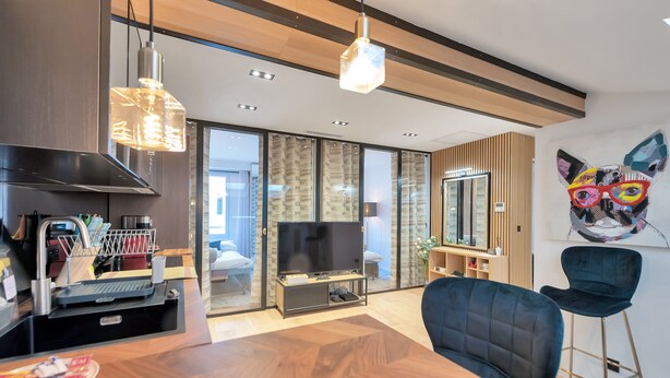 Una sala de estar moderna con una mesa de comedor de madera, un televisor y una pieza de arte original en la pared.