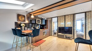 Una cocina moderna con comedor, televisor y un amplio ventanal.