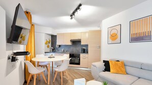 A modern kitchen with a dining area, a sofa, and a coffee table with plants. - Le Palme D'or près de la Croisette et Palais (Cannes)