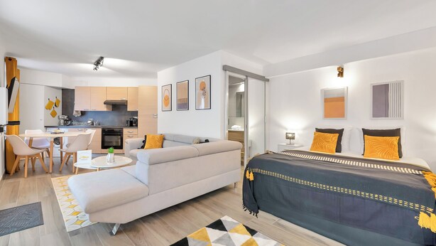 A modern apartment with a living area, kitchenette, and a bedroom with a bed and a sofa. - Le Palme D'or près de la Croisette et Palais (Cannes)