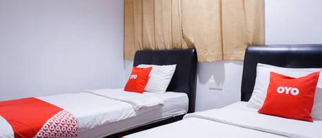 Two single beds with white and red bedding, a beige curtain, and a black headboard.