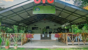 A covered outdoor area with a sign reading "OYO The 7-Lodge Tambunan" and tables and chairs arranged for dining. - Hotel O The 7 Lodge Tambunan (Tambunan)