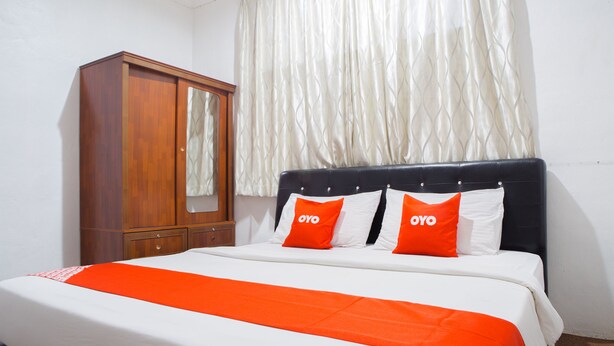 A bedroom with a bed, a wooden wardrobe, and a window with curtains. - Hotel O The 7 Lodge Tambunan (Tambunan)