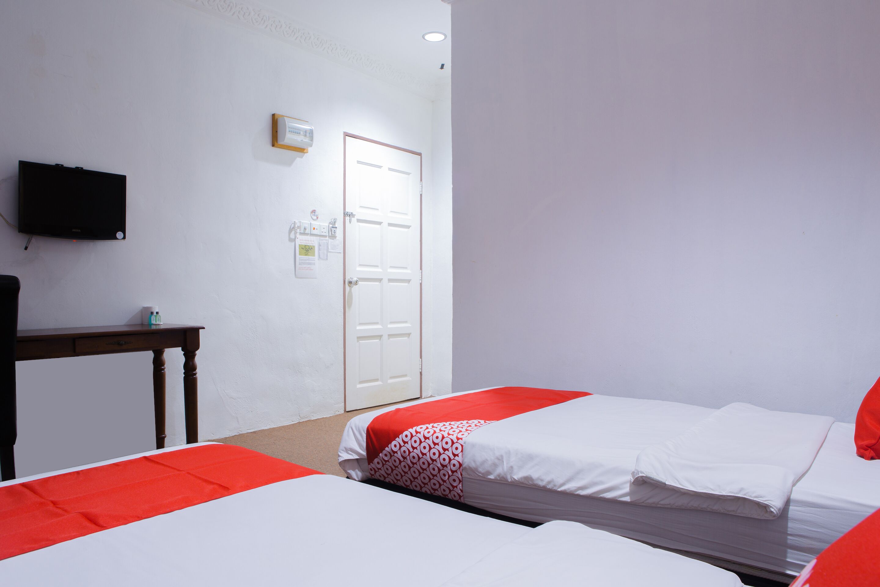 Une chambre d’hôtel avec deux lits, une télévision, un bureau et une porte.