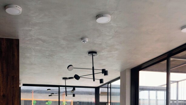 Una sala de estar moderna con un sofá modular, una mesa de centro de vidrio y un suelo con estampado geométrico.