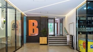 Un interior moderno con un llamativo letrero con la letra 'B', una escalera y una pared de vidrio que exhibe objetos.