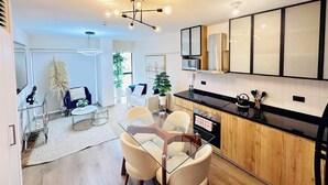 Una cocina moderna con armarios de madera, encimera negra y mesa de comedor de vidrio con sillas.