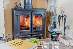 A cozy room with a wood-burning stove, wine glasses, and a book titled "City Country Coast". - Cosy yet stylish Cotswold holiday cottage - Rosewood Cottage (Blockley)