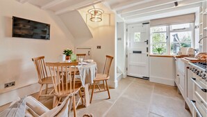 Una cucina con zona pranzo, sedie di legno, un tavolo e un lampadario.