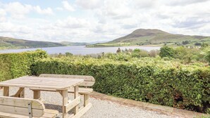 A wooden picnic table and bench overlooking a lake with hills in the background. - Craig Yr Ronwy (Bala)