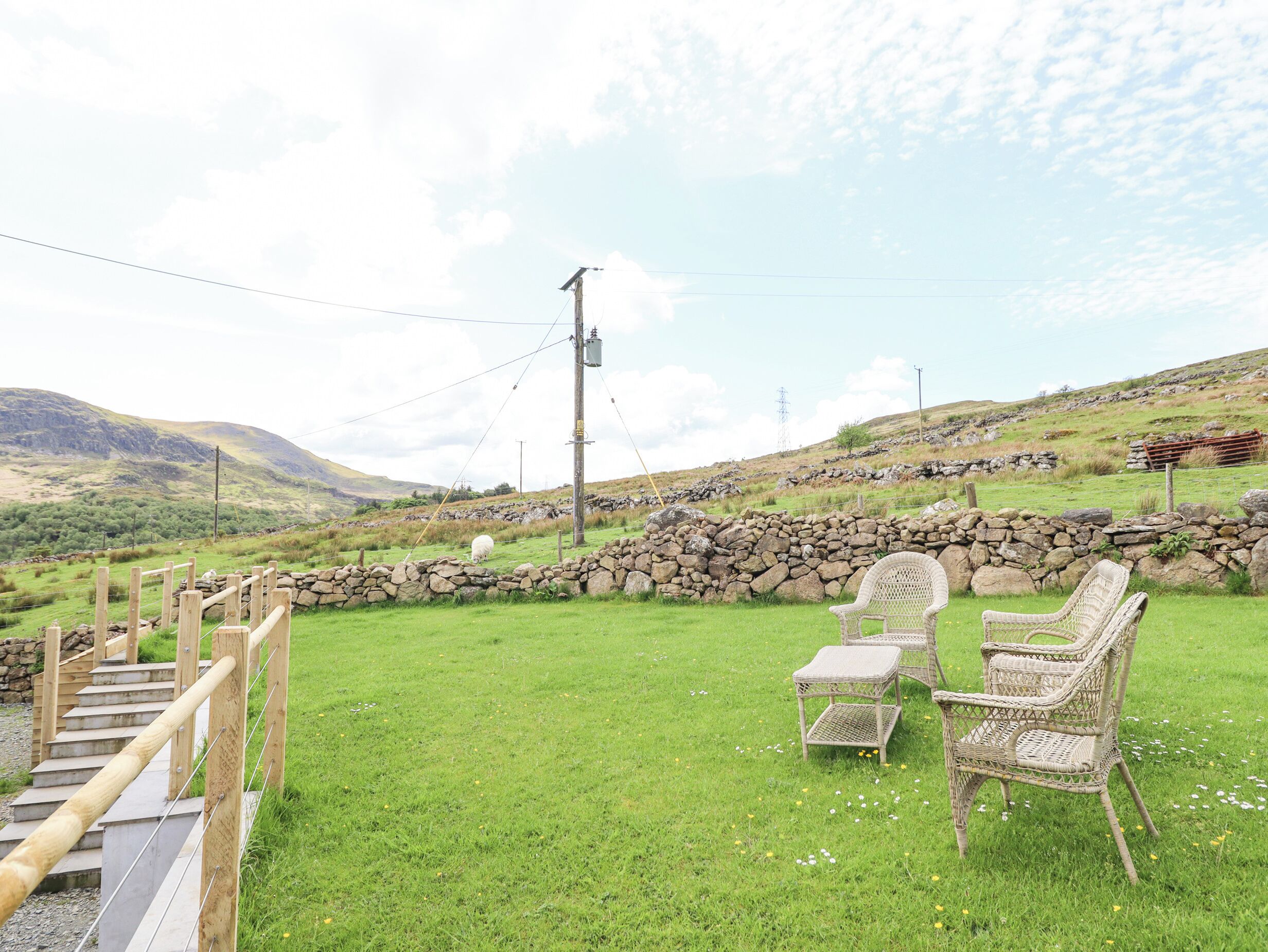 A grassy outdoor area with wicker furniture and a stone wall.