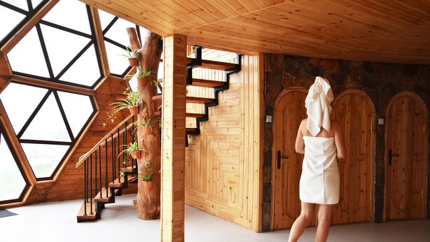 Un intérieur en bois avec un plafond aux motifs géométriques, un escalier et des portes en bois.