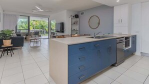A modern kitchen with a central island, built-in appliances, and a dining area with a view. - 3 Bedroom Poolside Drift North Apartment (Tweed)