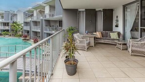 A balcony with a pool, wicker furniture, and a potted plant. - 3 Bedroom Poolside Drift North Apartment (Tweed)