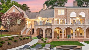 A large brick house with a pool, outdoor seating, and a well-maintained garden. - Waterfront, Pool & Dock | Shoreway Cove by AvantStay (Huntersville)