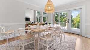 A dining area with a wooden table set for six, surrounded by white chairs with woven seats. - Waterfront, Pool & Dock | Shoreway Cove by AvantStay (Huntersville)