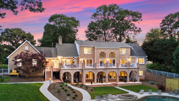 A large, multi-story house with a swimming pool, multiple balconies, and a well-maintained lawn. - Waterfront, Pool & Dock | Shoreway Cove by AvantStay (Huntersville)