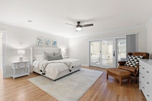A bedroom with a bed, a nightstand, a chair, a dresser, and a ceiling fan.