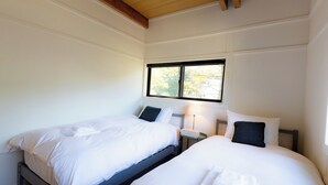 A hotel room with two beds, a window, and a nightstand with a lamp. - KONAYUKI CABIN HAKUBA (Hakuba)