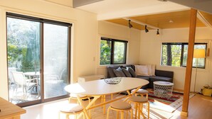 A modern living space with a dining area, sofa, and large windows. - KONAYUKI CABIN HAKUBA (Hakuba)