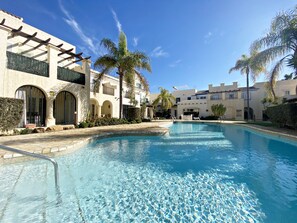 A pool area with clear blue water, surrounded by buildings with balconies and arched doorways. - LC 43 - Holiday rental near the beach (Vera playa)