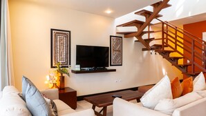 A living room with a sofa, coffee table, and a TV mounted on the wall.