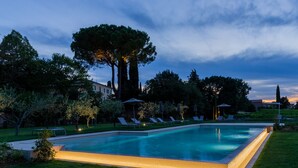 Una piscina rectangular con césped cuidado y sillones de descanso alrededor.