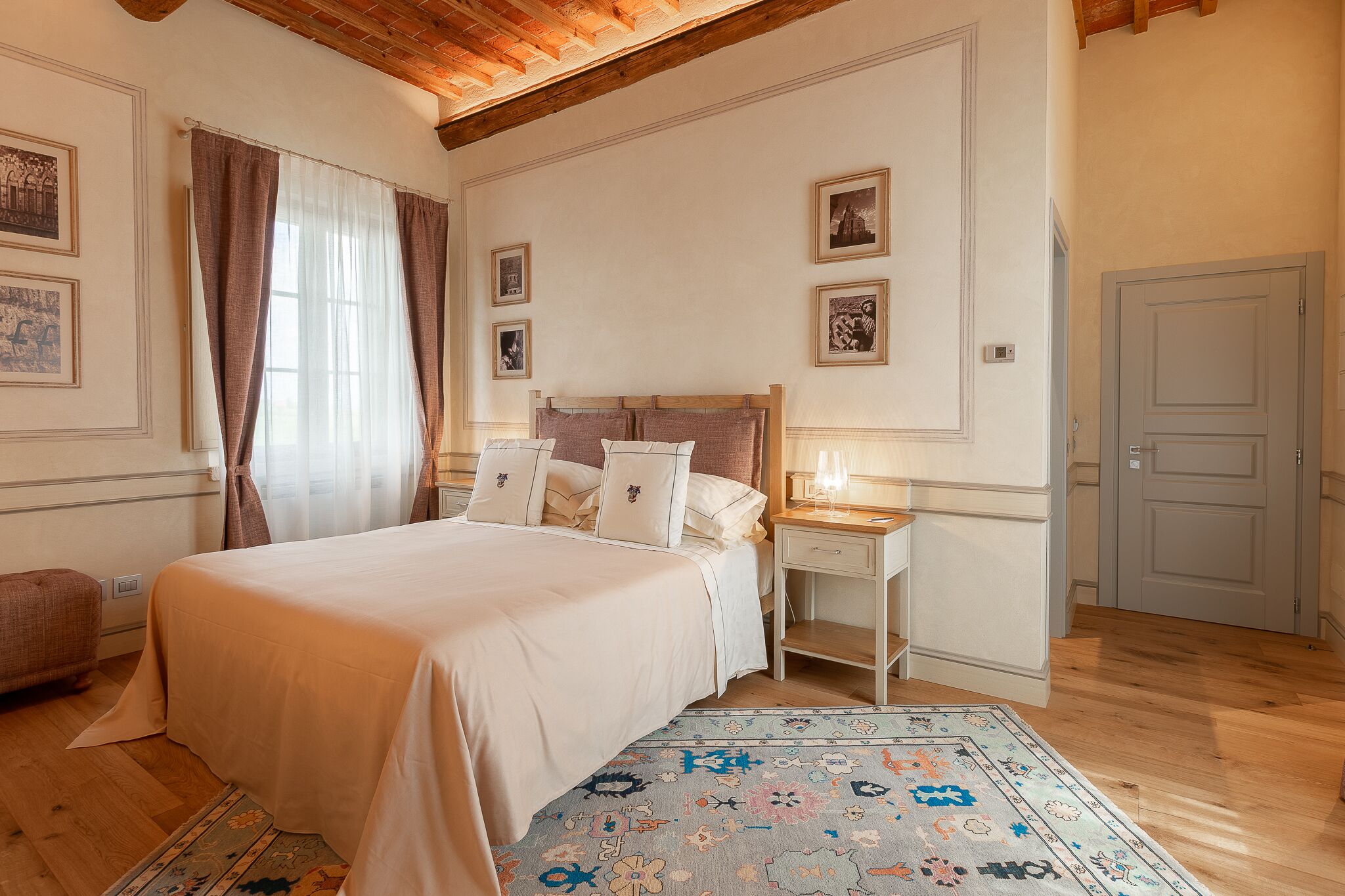 Quarto com uma cama grande, mesa de cabeceira, abajur e porta.