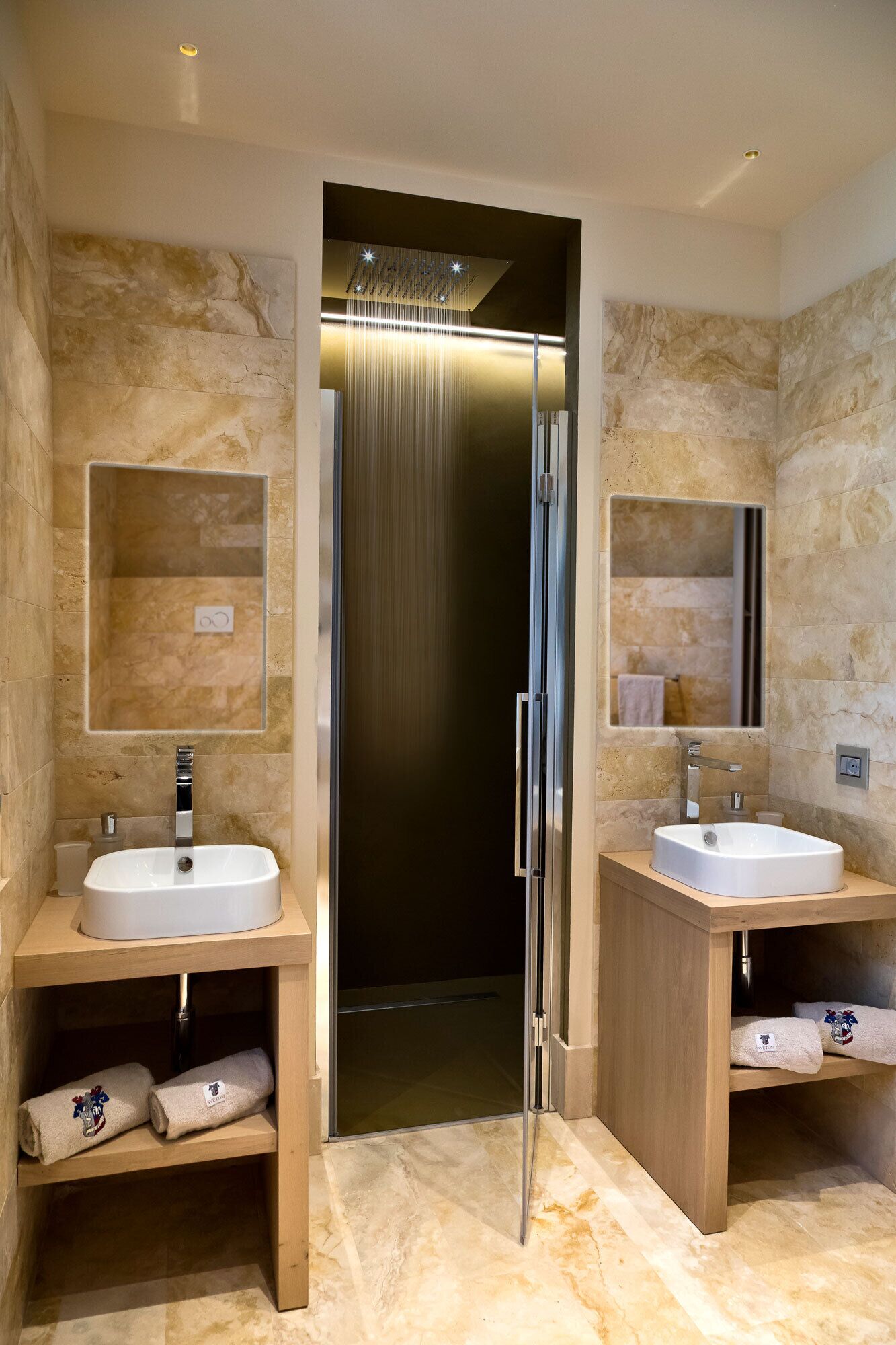 Ein modernes Badezimmer mit zwei Waschbecken, einer Dusche und einer Glasabtrennung.