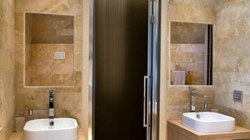 Ein modernes Badezimmer mit zwei Waschbecken, einer Dusche und einer Glasabtrennung.