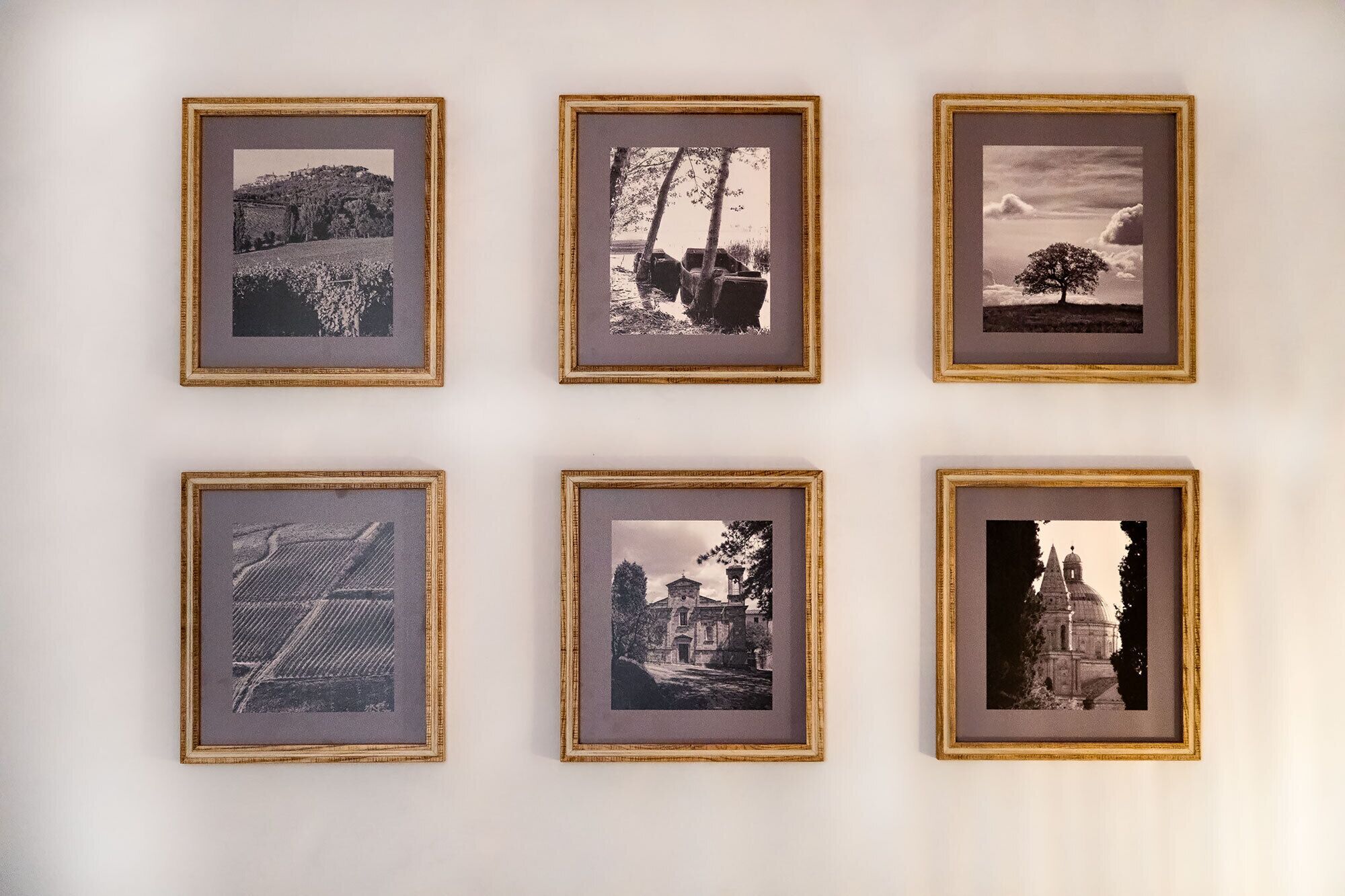 Sechs gerahmte Fotografien verschiedener Landschaften und Gebäude an einer Wand.