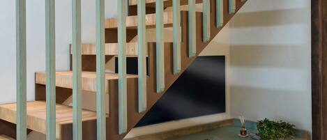 Una escalera con escalones de madera y barandillas azul verdosas, que conduce a un rellano con superficie plana.