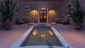 Un patio con una fuente central, paredes de piedra y zonas de estar.
