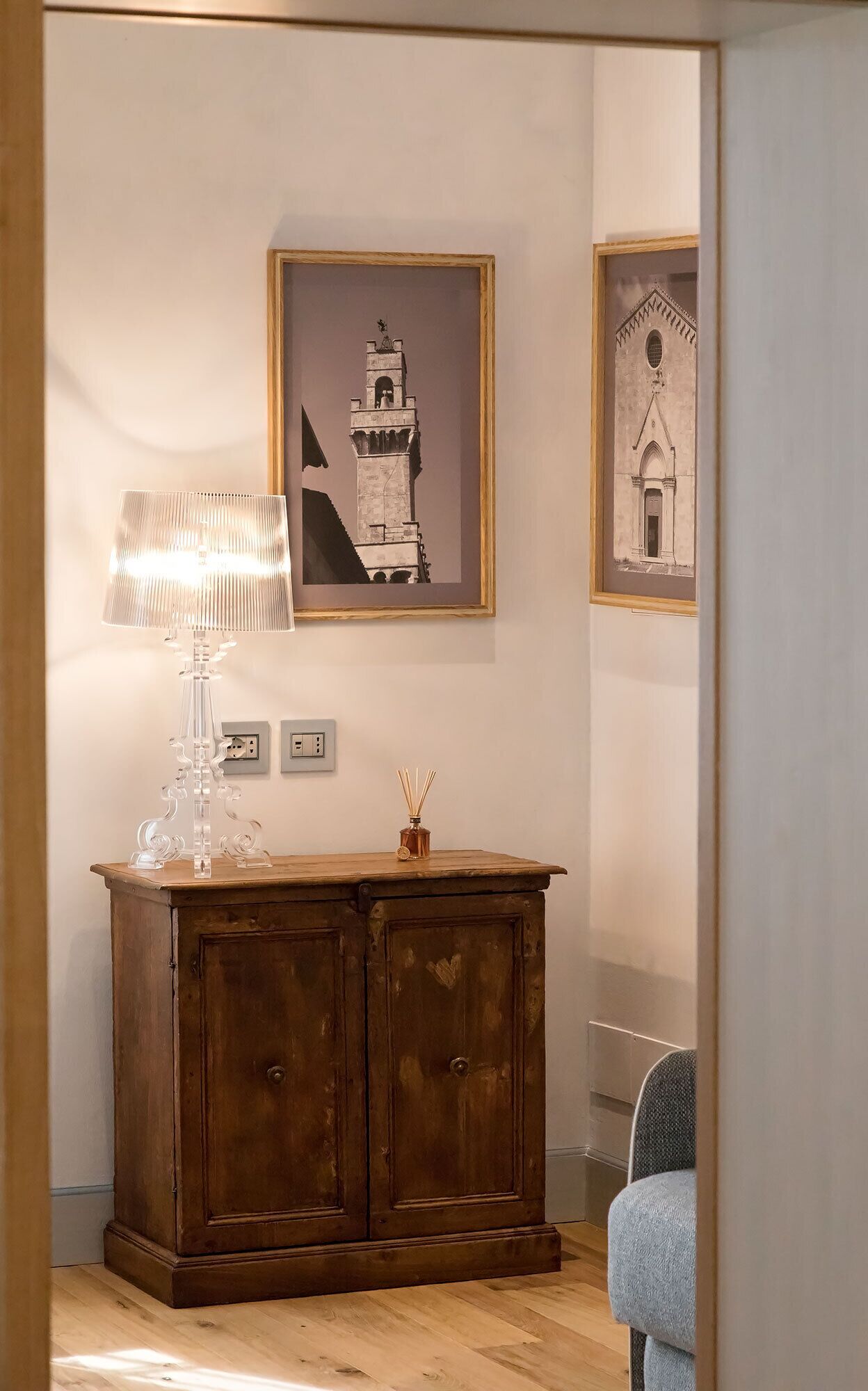 A wooden cabinet with a lamp and a picture frame on the wall.
