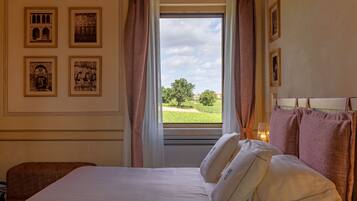 A hotel room with a bed, a window with curtains, and four framed pictures on the wall.