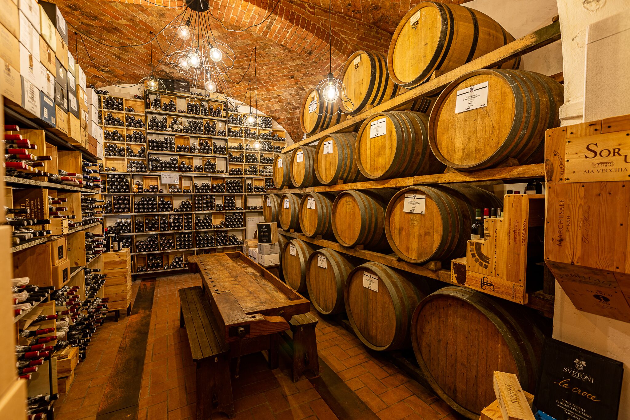 Une cave à vin avec des barriques en bois et des étagères remplies de bouteilles de vin.