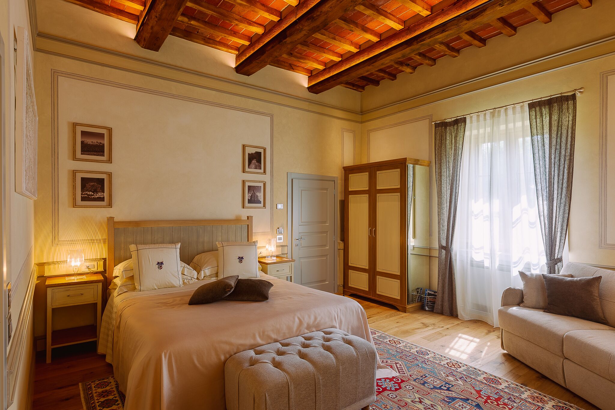 A bedroom with a large bed, a nightstand, a dresser, a wardrobe, and a sofa.