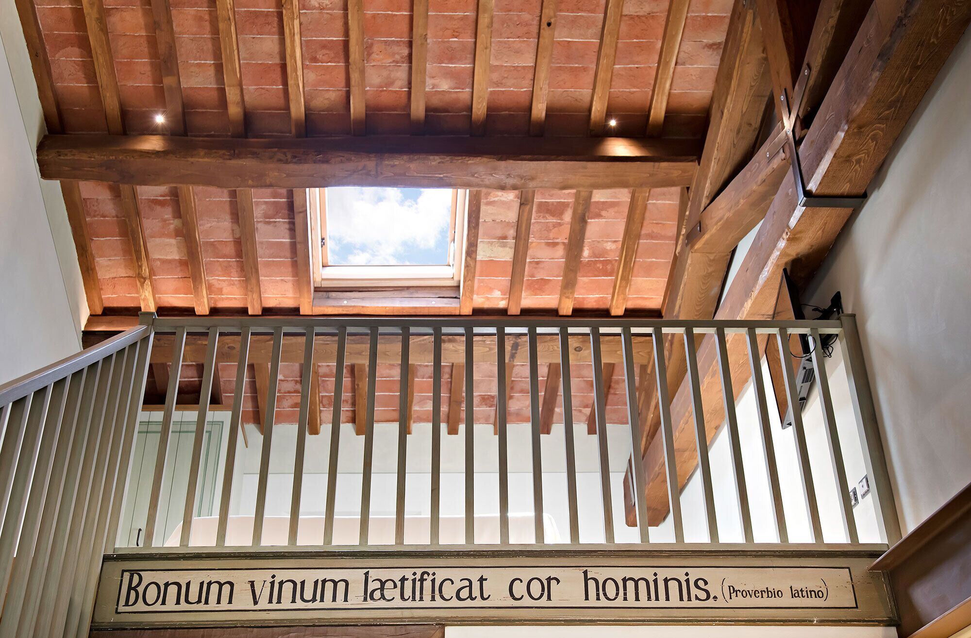Ein Holzbalkon mit einem Metallgeländer und einem Schild, auf dem steht: Bonum vinum laetificat cor hominis.