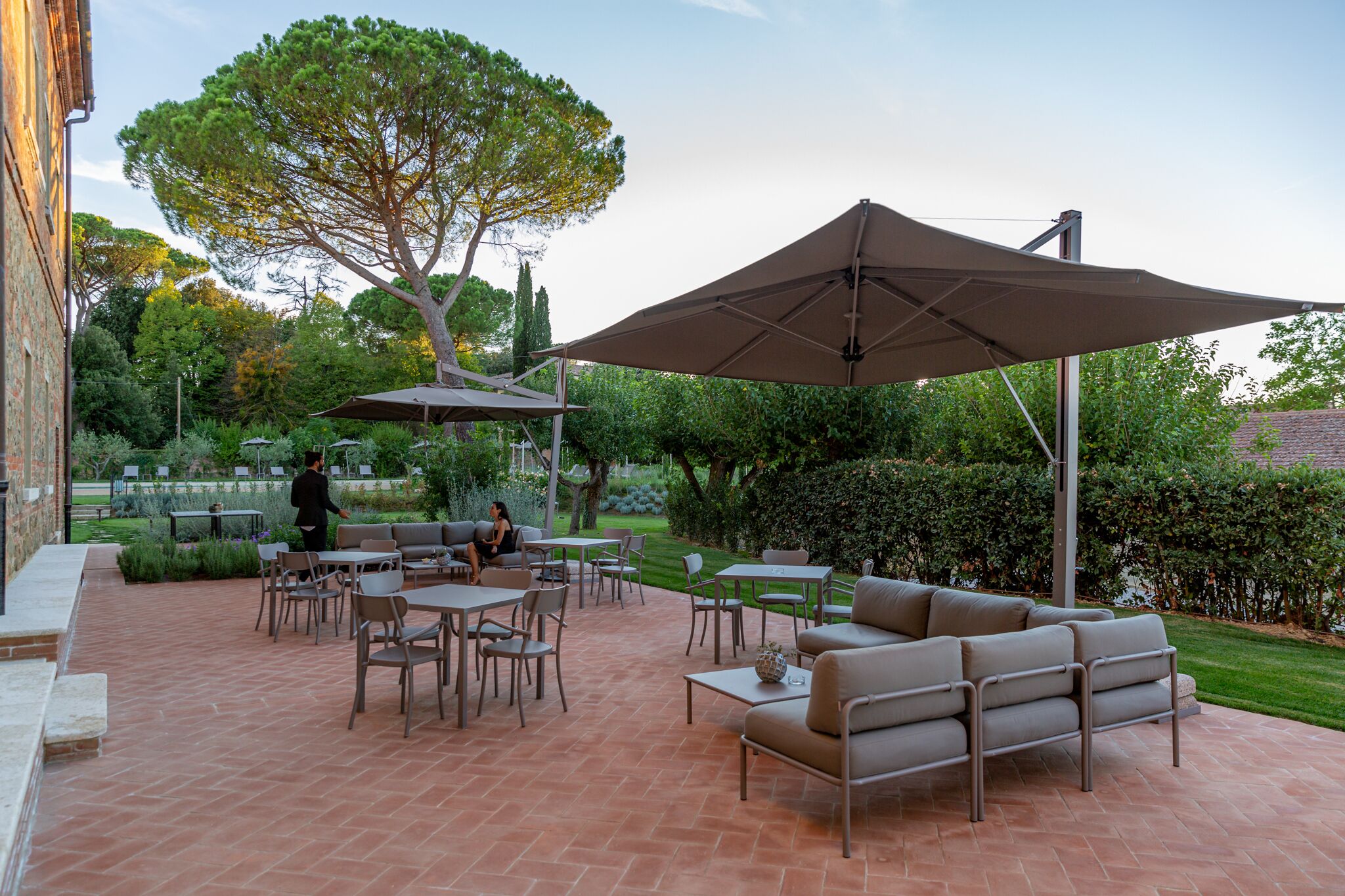 An outdoor patio with tables, chairs, and a large umbrella.