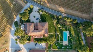 Vista aérea de una propiedad residencial con una casa grande, una piscina y jardines circundantes.