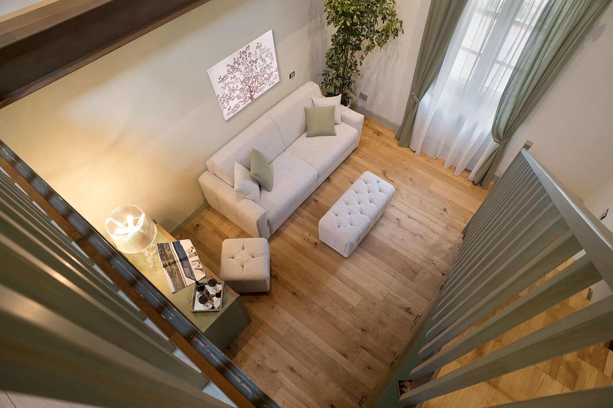 A modern living room with a sofa, ottoman, and a coffee table with drinks.