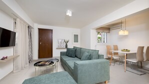 Una sala moderna con sofá, reposapiés y comedor con sillas y una mesa.