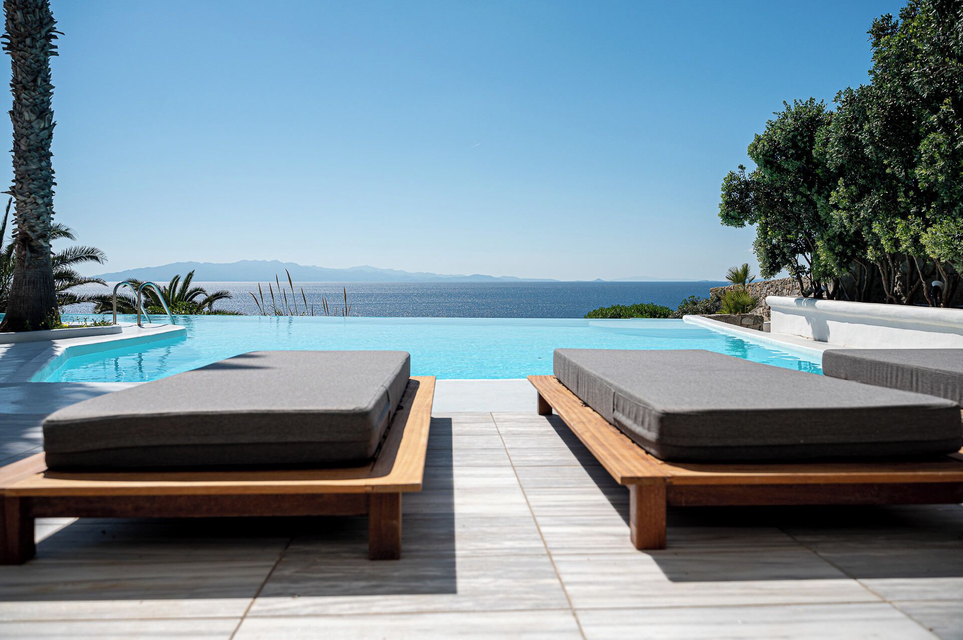 A poolside area with lounge chairs and a view of the sea.