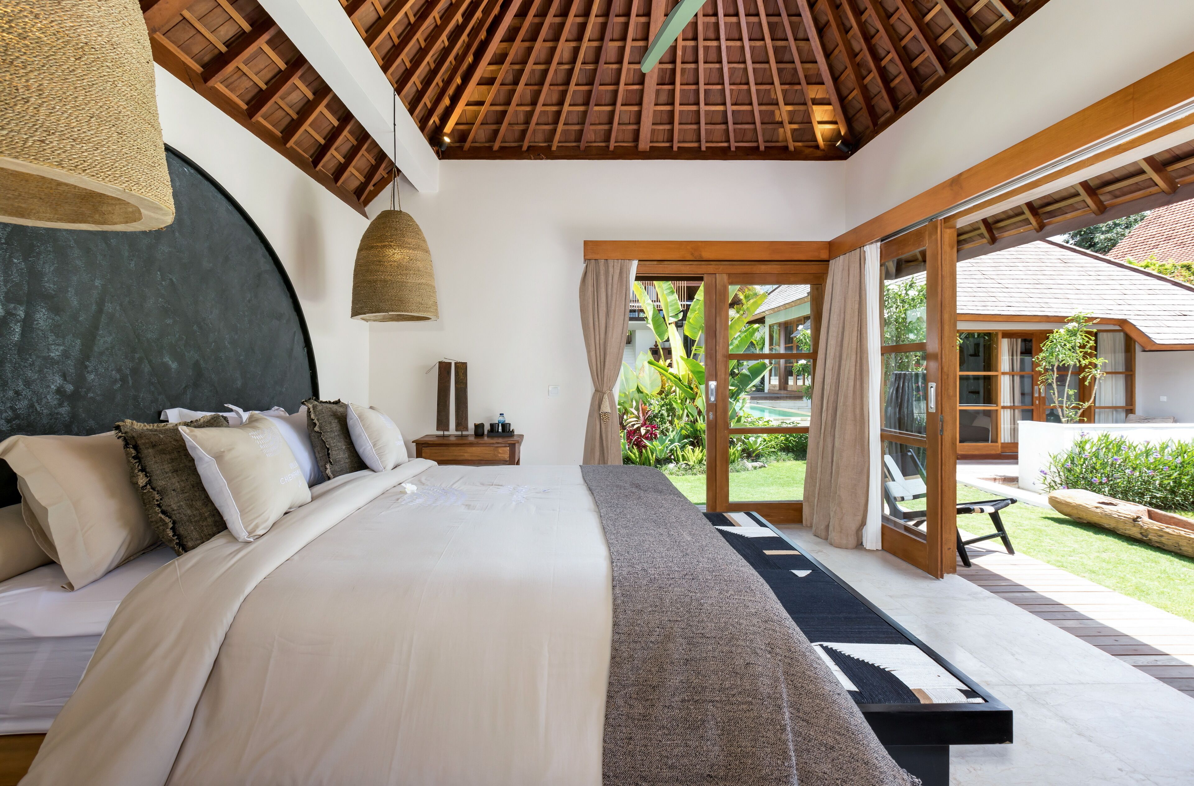 Un dormitorio con una cama grande, techo de madera y vistas al jardín.