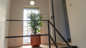 Eine Treppe mit Holzboden, einem Blumentopf und einer modernen Leuchte.
